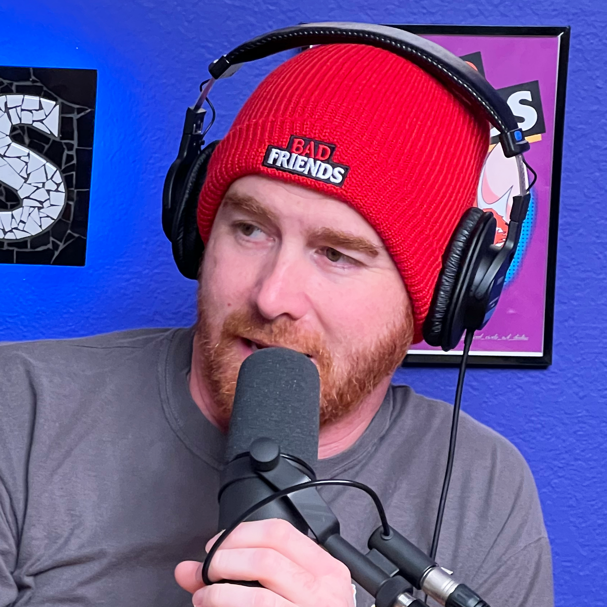 Andrew Wearing Red Embroidered Bad Friends Beanie at his podcast chair